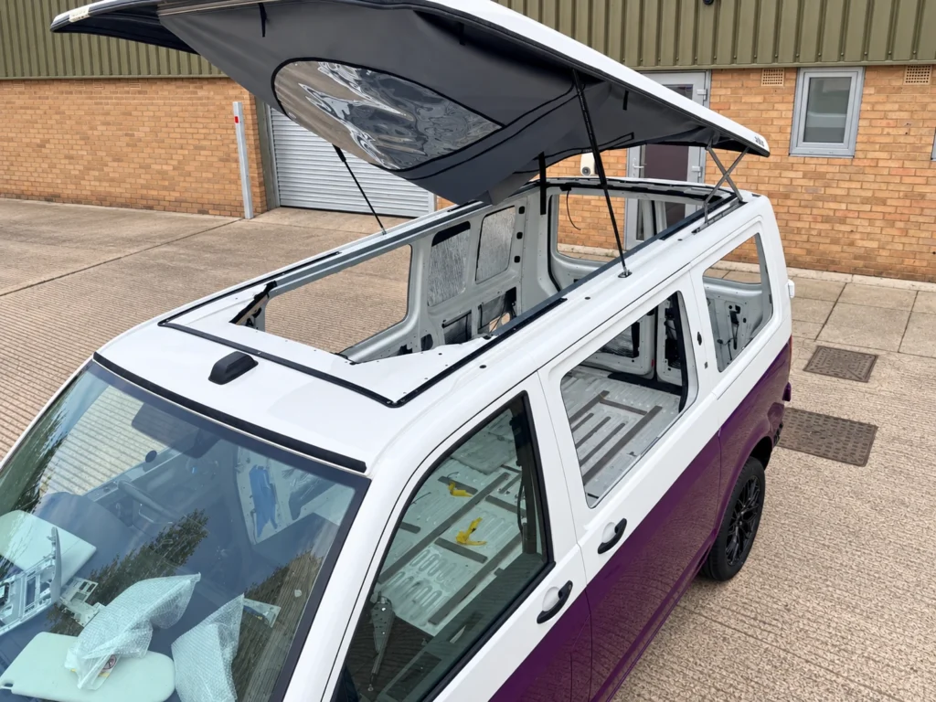 Pop-top roof installation in progress on a white and purple VW Transporter at Vanlord’s Wellingborough workshop